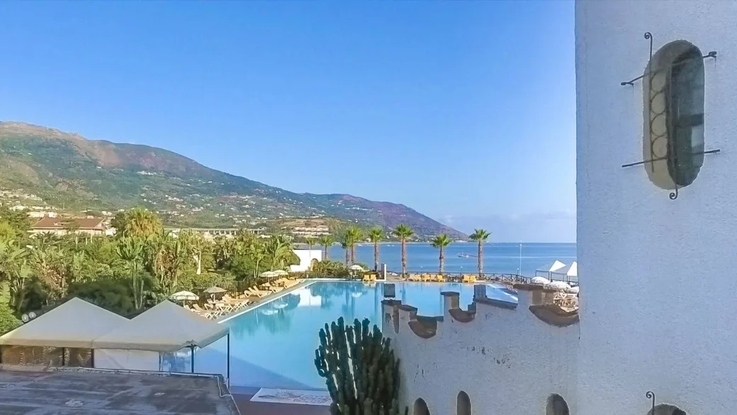 Vista della piscina e del mare con montagne dall'edificio dell'hotel