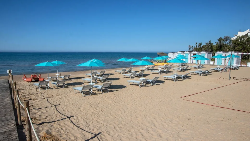 Spiaggia di sabbia con lettini e ombrelloni azzurri sul mare