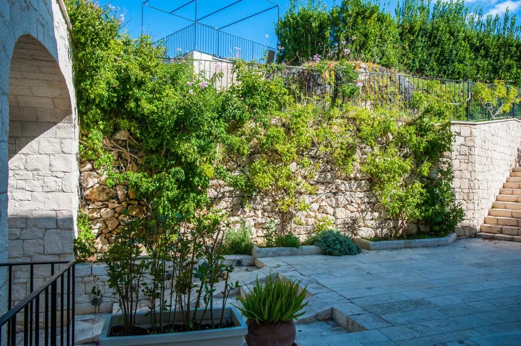 Cortile in pietra con muro fiorito e scalinata esterna