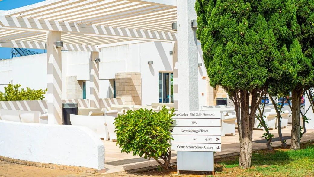 Area esterna con pergola bianca e cartelli indicatori dei servizi del resort