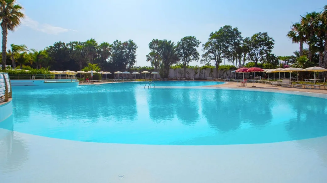 Grande piscina laguna con palme e ombrelloni intorno