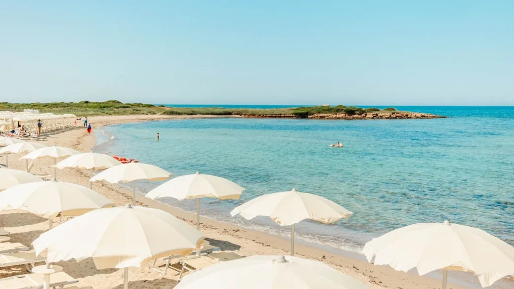 Spiaggia con ombrelloni bianchi e mare azzurro in una giornata di sole