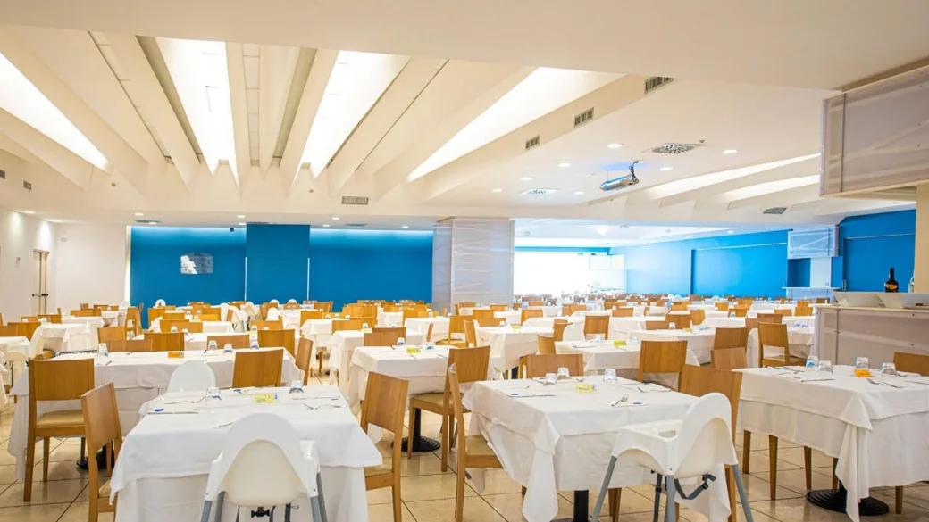 Ampia sala ristorante interna con tavoli apparecchiati e parete blu