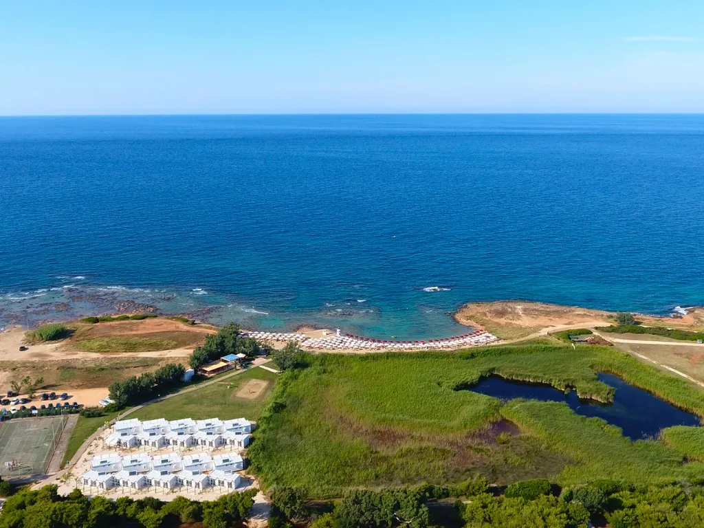 Panoramica aerea della costa con casette bianche, spiaggia e mare blu profondo