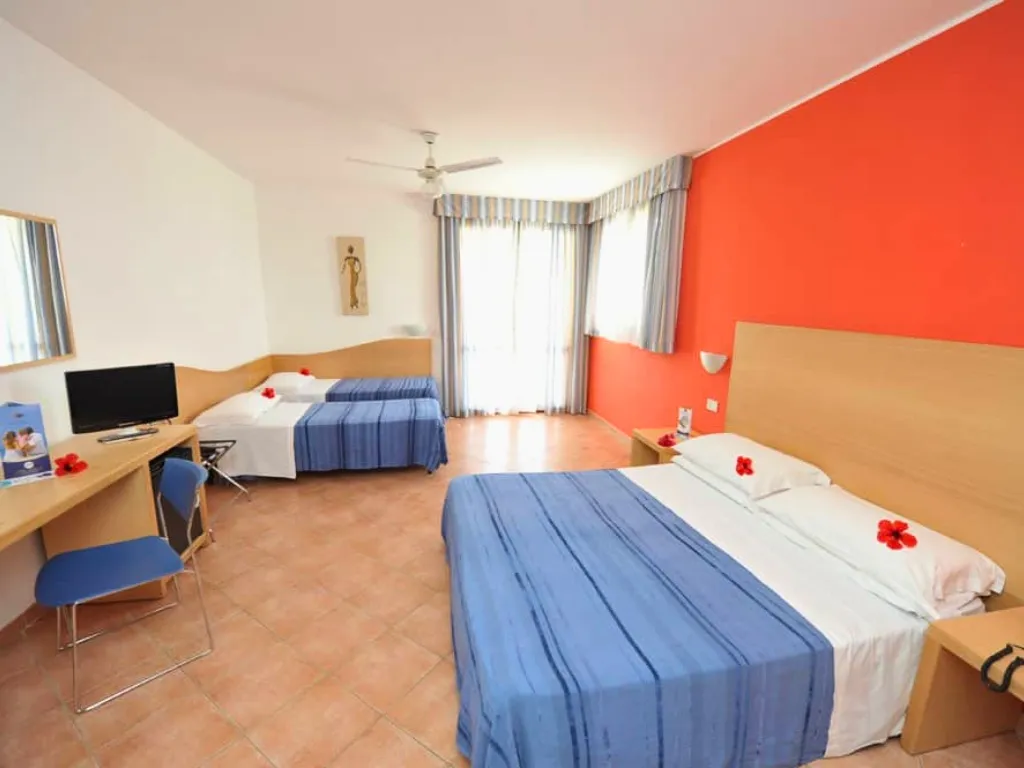 Camera familiare con letto matrimoniale, letto singolo, scrivania e parete arancione