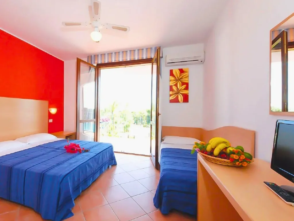 Camera con letto matrimoniale, letto singolo, parete rossa e porta finestra sul balcone
