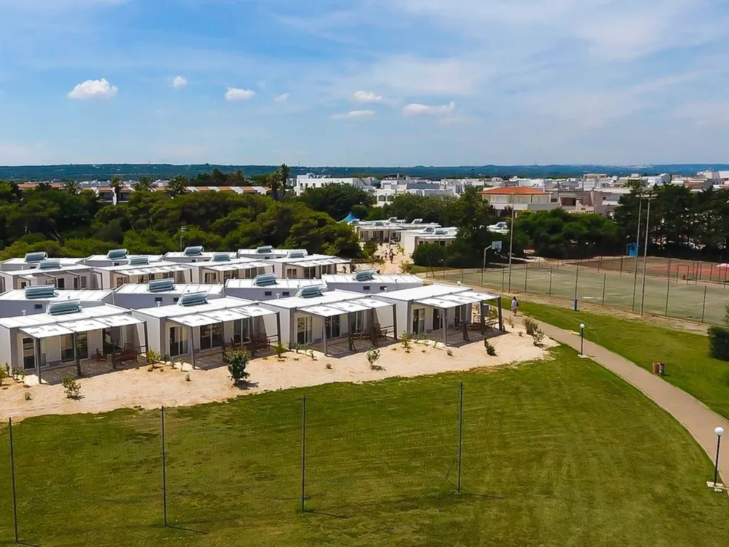 Vista aerea delle casette bianche del resort con verande e campi sportivi