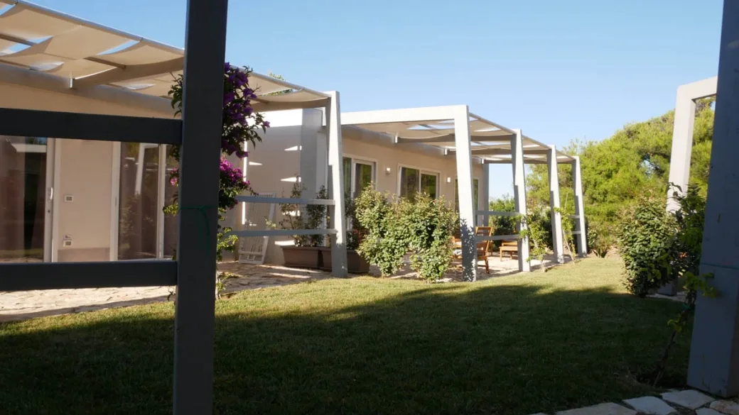 Bungalow con pergolato bianco, veranda e giardino con bouganville viola