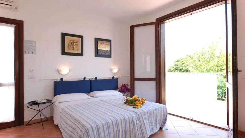 Camera luminosa con letto matrimoniale, testiera blu e porta finestra sul balcone