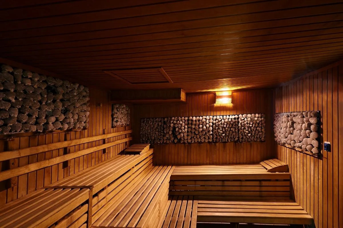 Sauna finlandese in legno con pareti in pietra e illuminazione soffusa