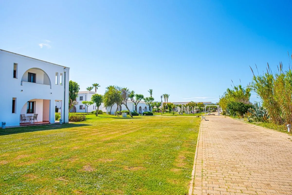 Ampio prato verde con vialetto e edifici bianchi del resort