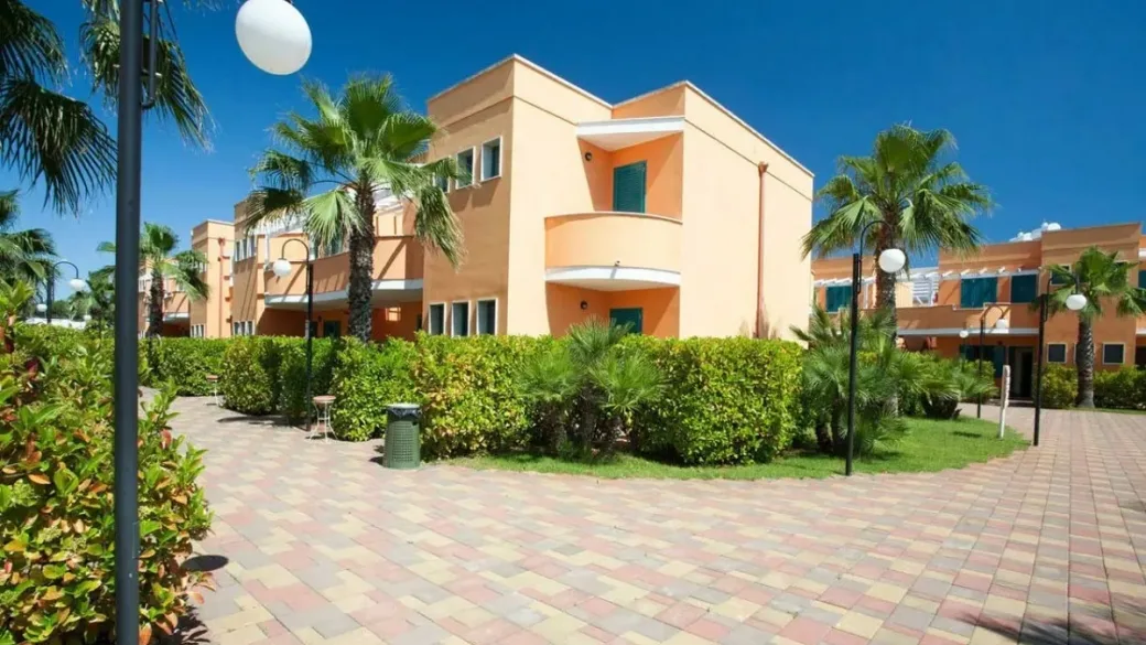 Palazzine del resort con balconi e palme sotto cielo azzurro