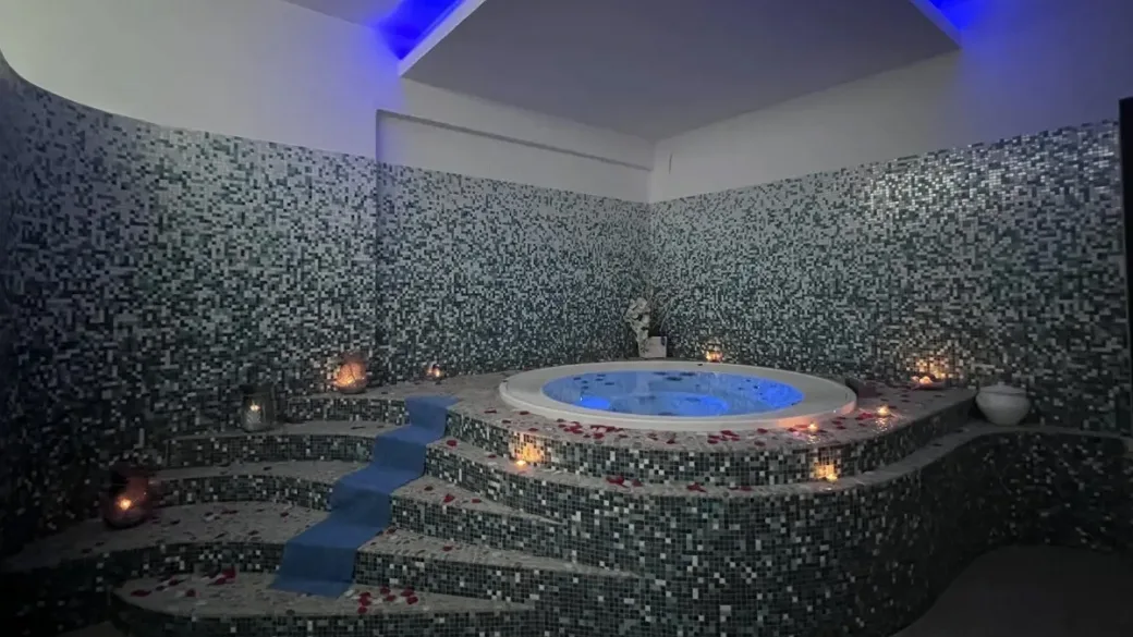 Vasca idromassaggio con mosaico, candele e petali di rosa nella spa
