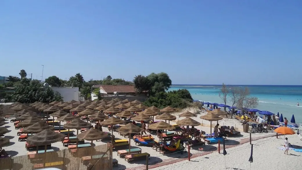 Spiaggia con ombrelloni in paglia colorati e mare turchese