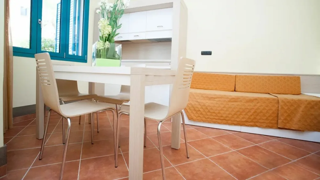 Interno di appartamento con tavolo da pranzo, sedie e divano arancione