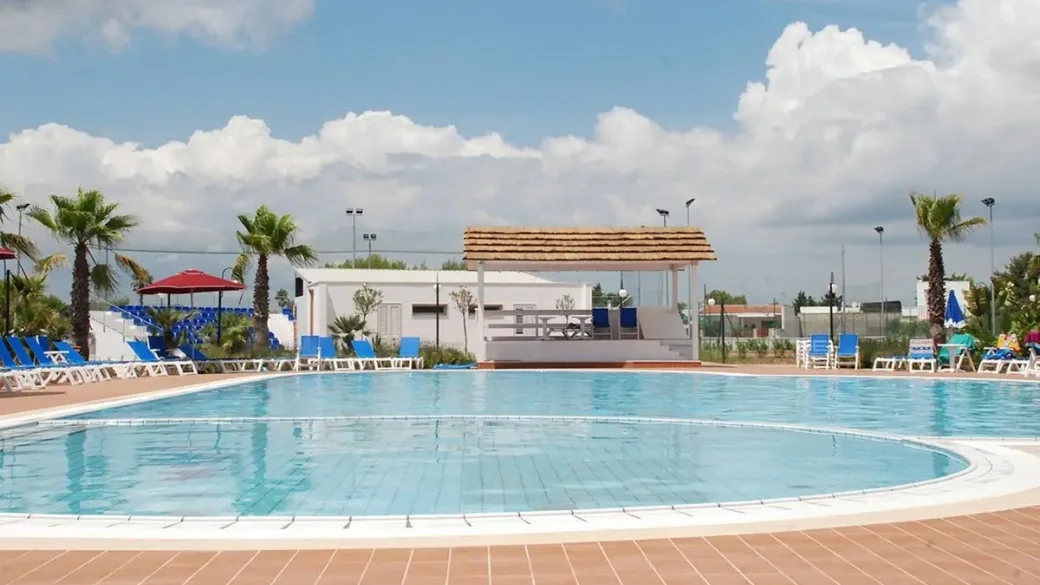 Piscina con gazebo e sedute blu sotto cielo nuvoloso