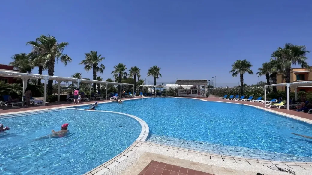 Piscina panoramica con palme e pergolati bianchi
