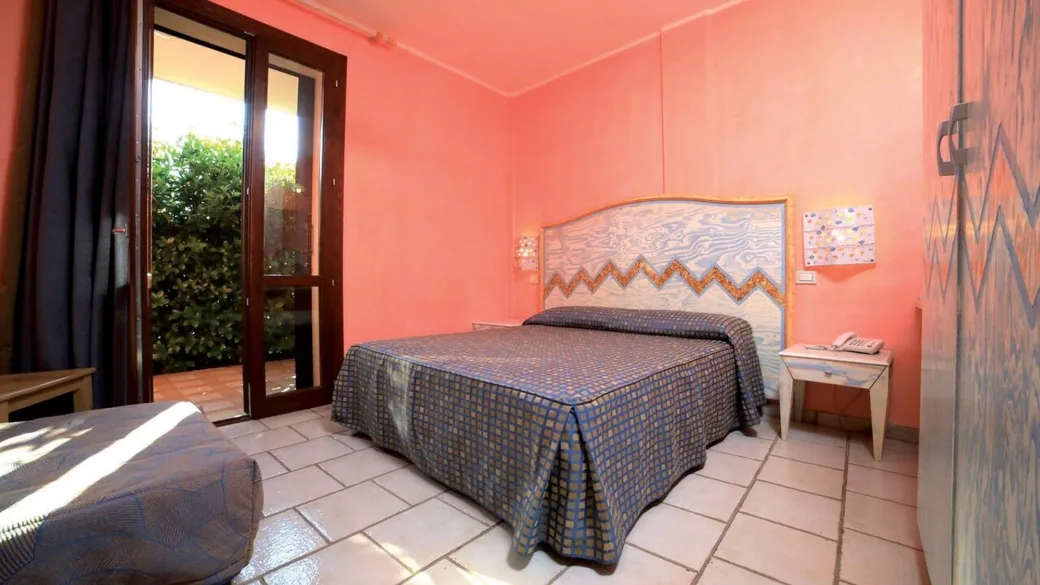 Camera da letto con pareti rosa, letto matrimoniale e accesso al patio sul giardino