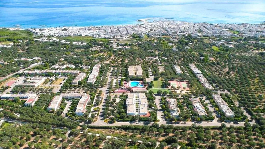 Veduta aerea del villaggio turistico con piscina e vista sul mare all'orizzonte