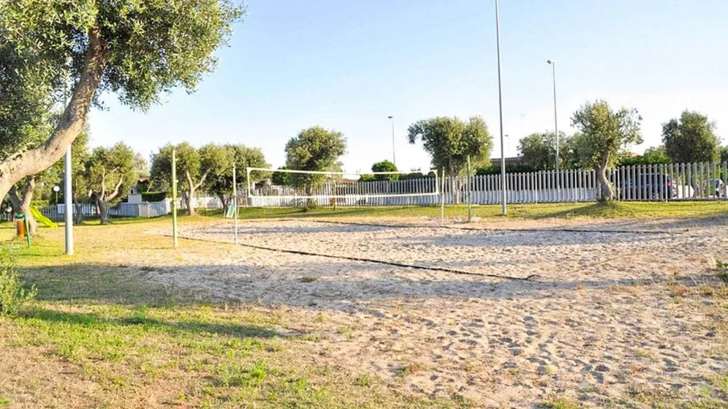 Campo da beach volley su sabbia circondato da ulivi e recinzione bianca