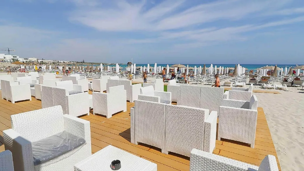 Area lounge sulla spiaggia con poltrone bianche in rattan e vista sul mare