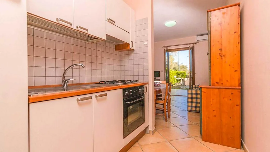 Angolo cottura con lavello, forno e mobili bianchi con vista sulla zona pranzo
