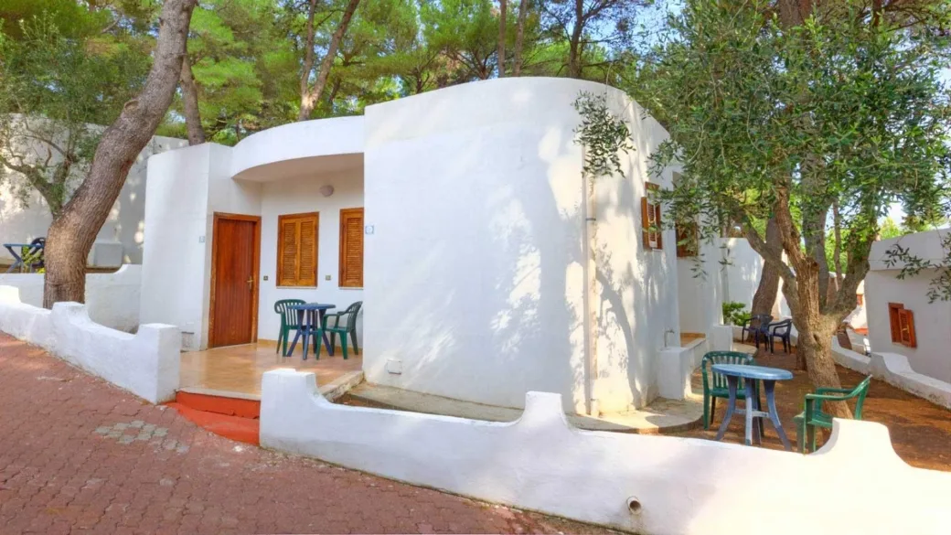 Esterno di bungalow bianco con veranda, tavolini e alberi