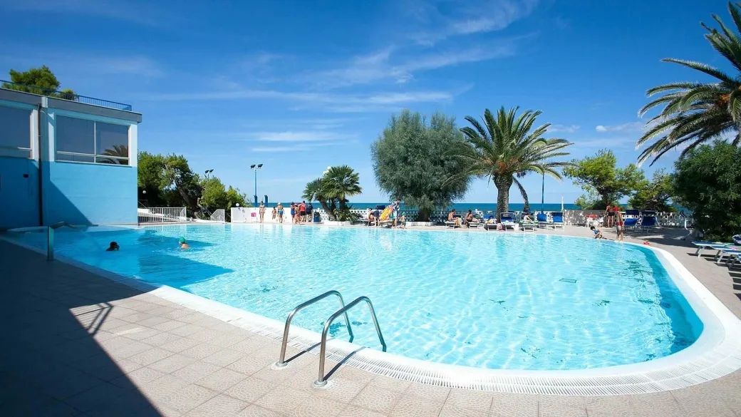 Piscina esterna con palme, lettini e vista sul mare