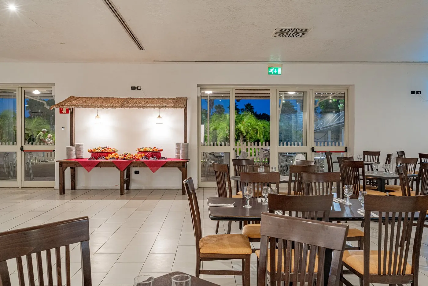 Sala ristorante interna con tavoli apparecchiati e buffet di frutta