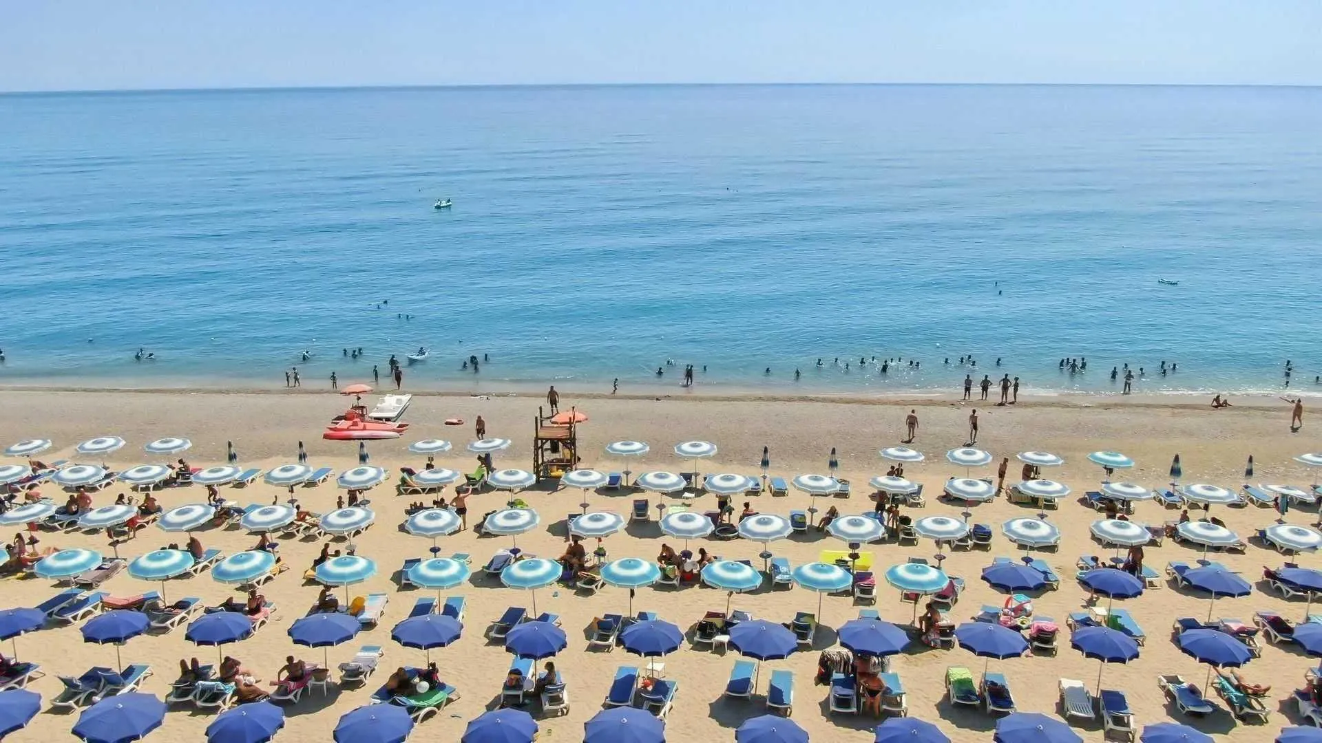 Spiaggia attrezzata con ombrelloni e lettini blu davanti al mare