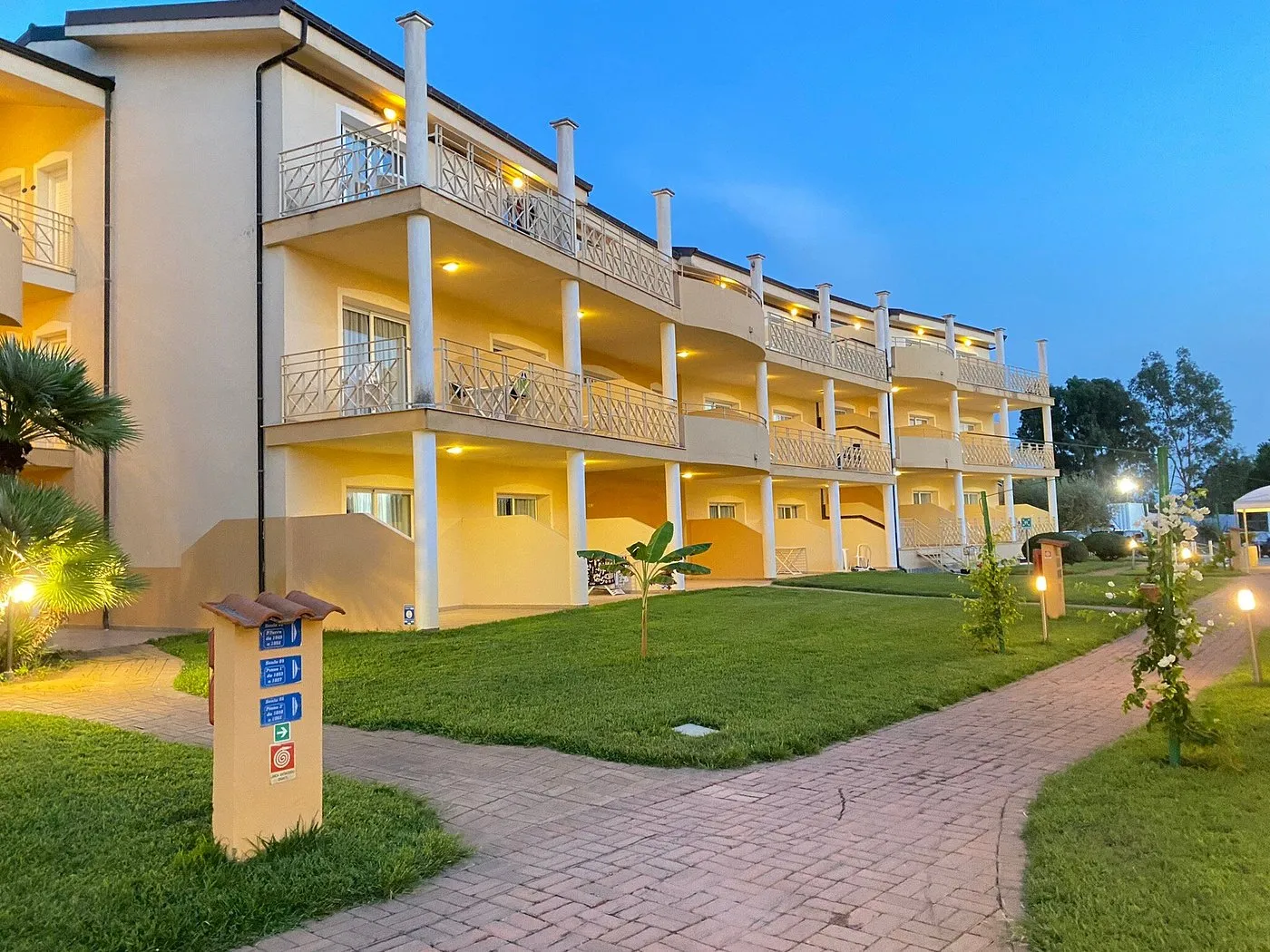 Edificio del resort illuminato al tramonto con balconi e giardino curato