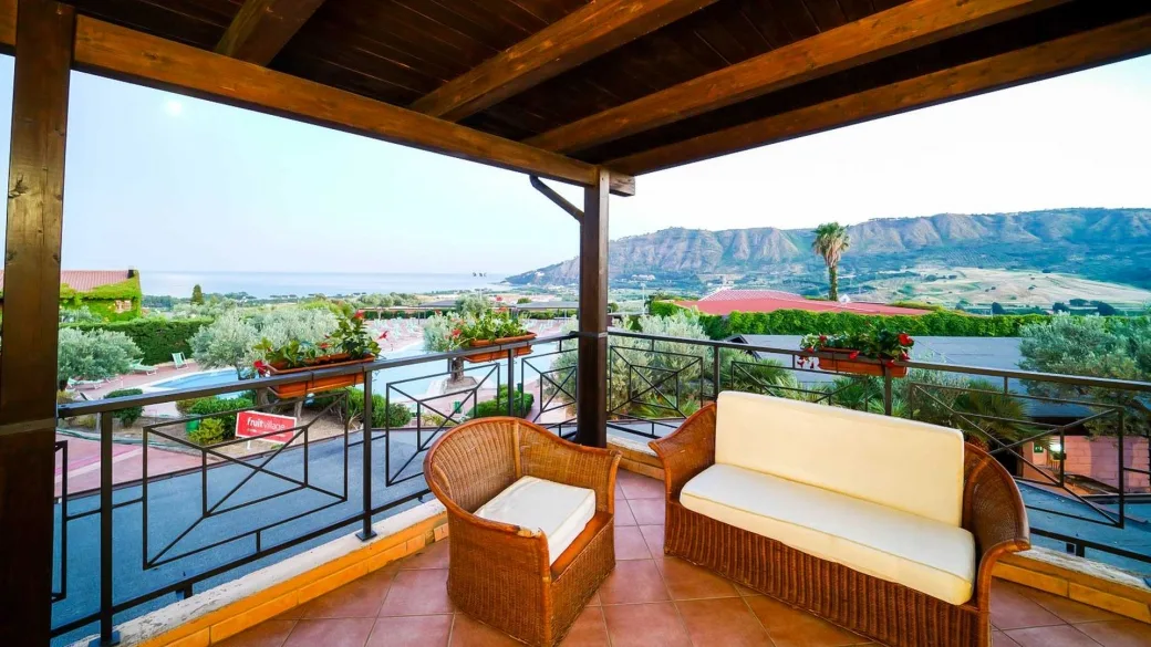 Balcone con divano e poltrona in vimini e vista panoramica sul mare e colline
