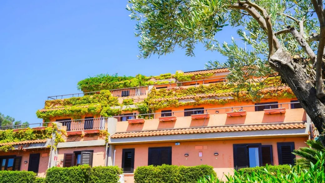 Edificio color terracotta con terrazze fiorite e vegetazione rampicante
