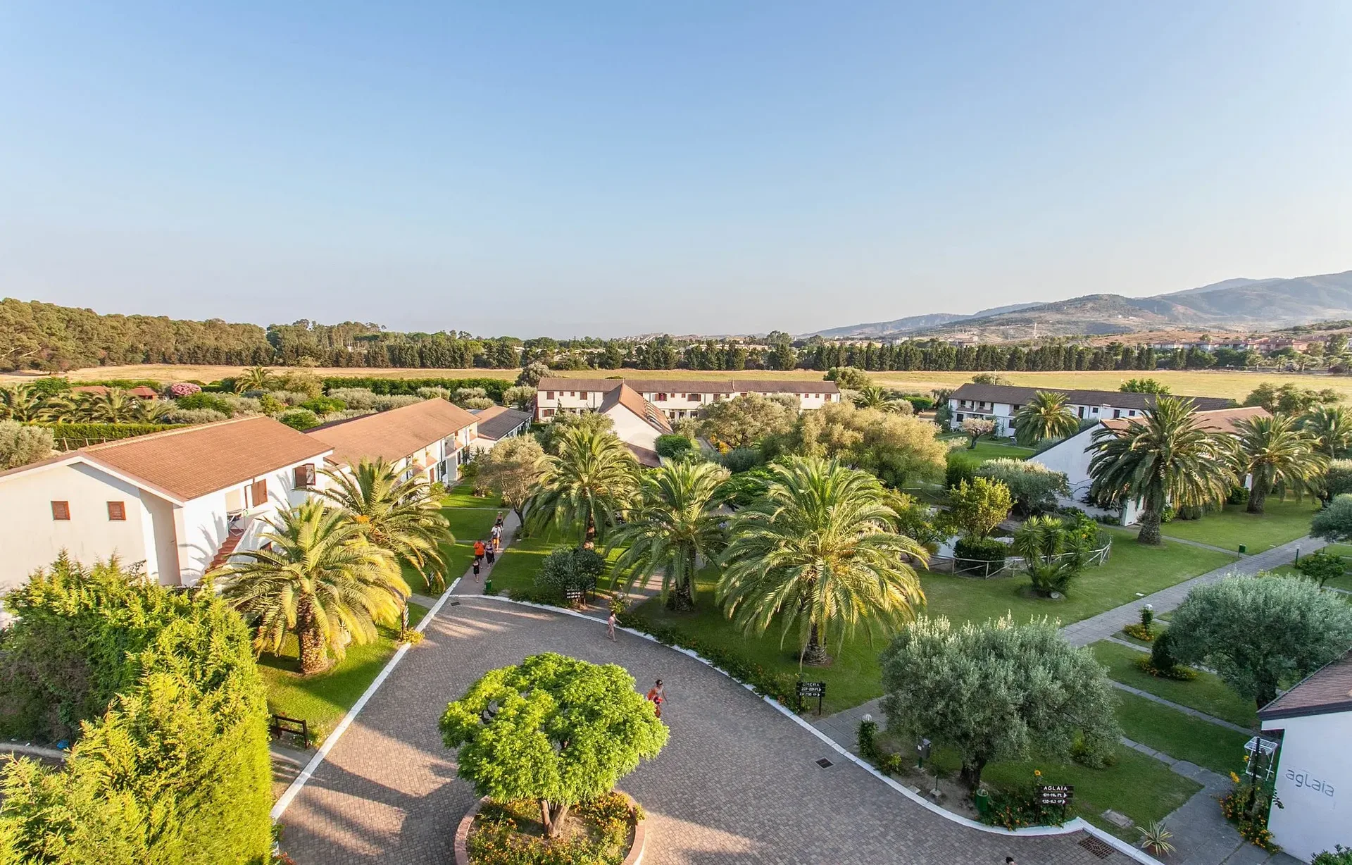 Veduta aerea del villaggio con palme, giardini curati e alloggi bianchi