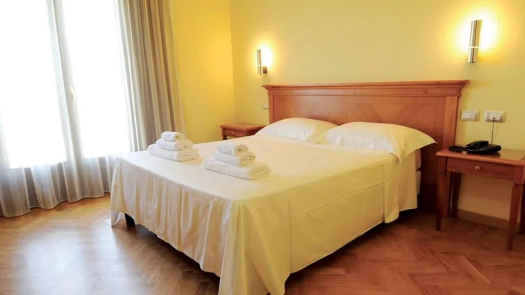 Camera con letto matrimoniale, testiera in legno e pavimento in parquet