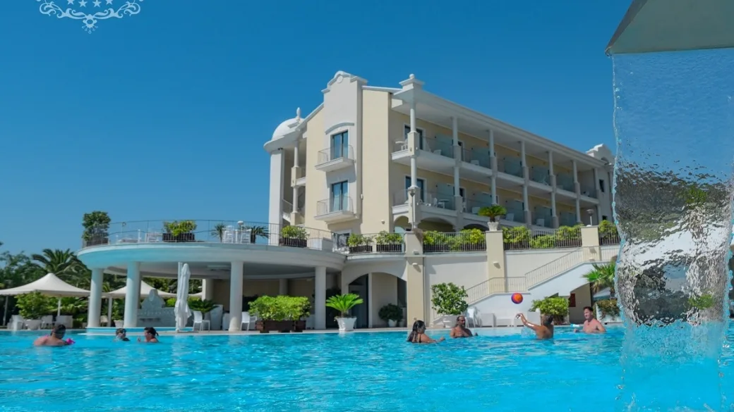 Facciata dell'hotel con piscina, cascata d'acqua e ospiti in vacanza