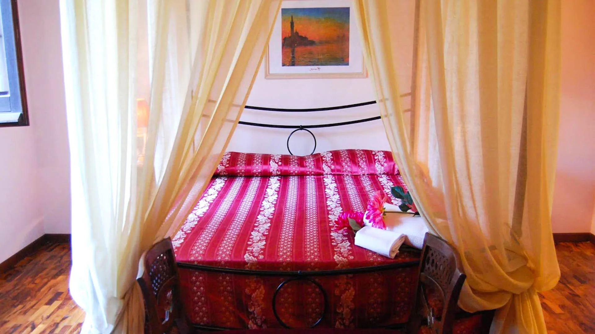 Letto a baldacchino con copriletto rosso e tende chiare