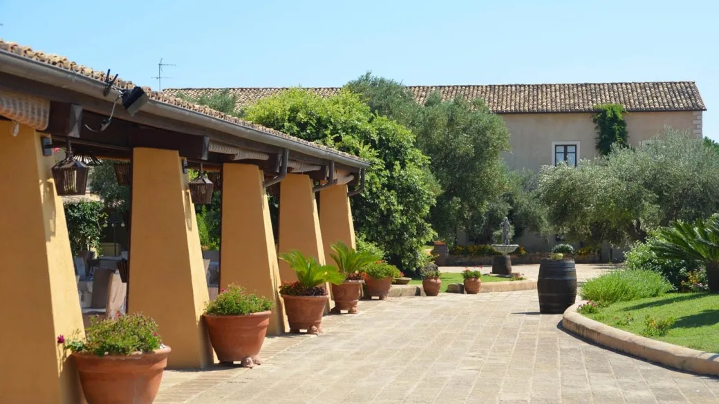 Vialetto pavimentato con portico, fontana e piante in vaso in terracotta