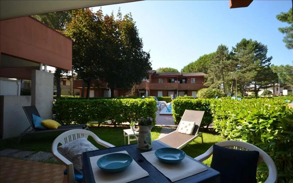 Veranda con tavolo apparecchiato e lettini affacciata sul giardino e la piscina