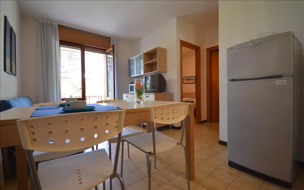 Zona pranzo con tavolo, sedie e frigorifero vicino alla finestra