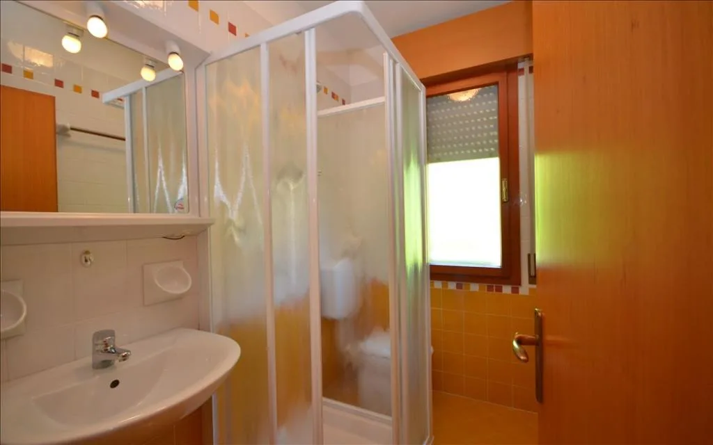 Bagno con lavabo, specchio e box doccia in toni arancioni