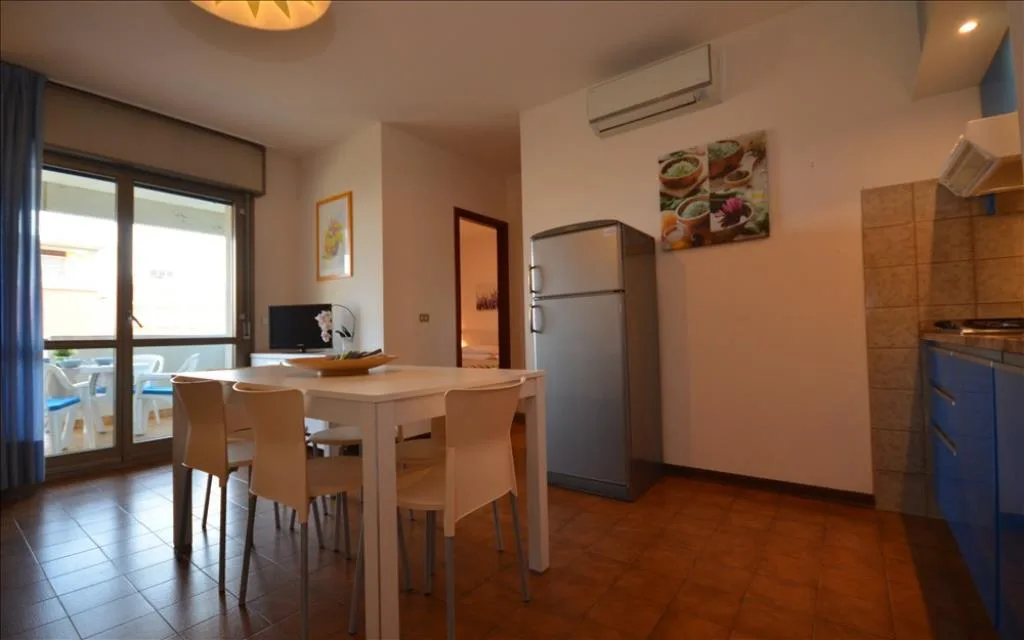 Cucina abitabile con tavolo, sedie e frigorifero