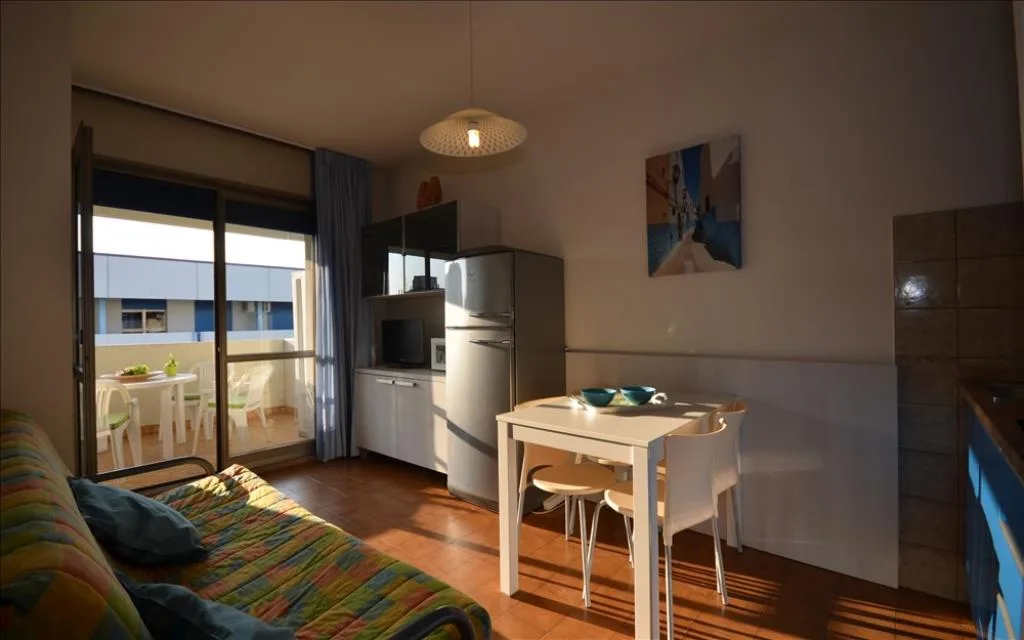 Zona giorno con divano, tavolo e accesso al balcone