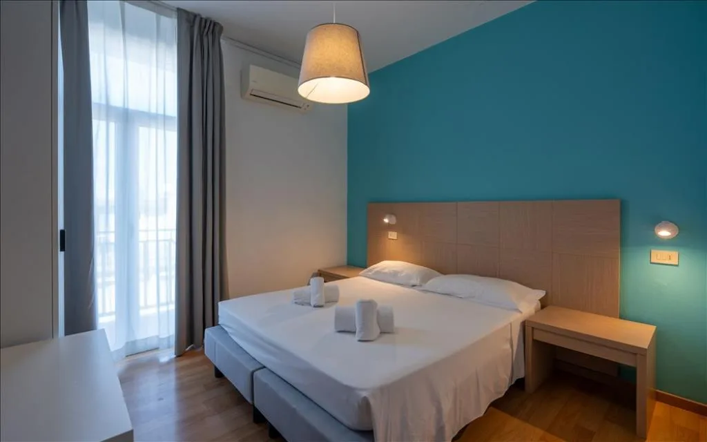 Camera moderna con parete turchese, letto matrimoniale e testiera in legno