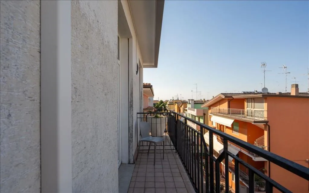 Balcone con sedia e vista su edifici colorati e tetti sotto cielo azzurro