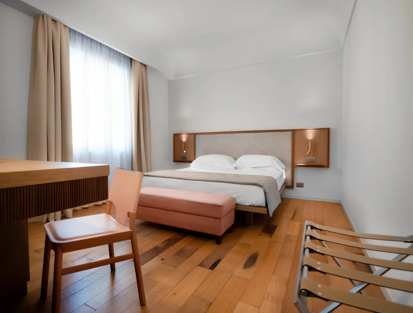 Camera luminosa con letto matrimoniale, panca e pavimento in parquet
