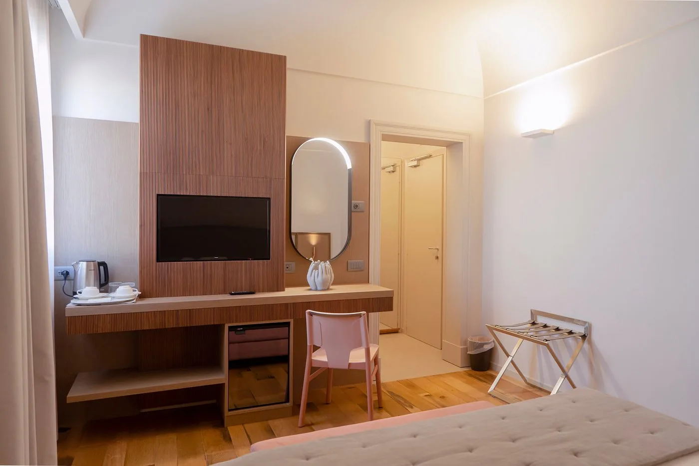 Camera con scrivania in legno, specchio ovale e TV a parete