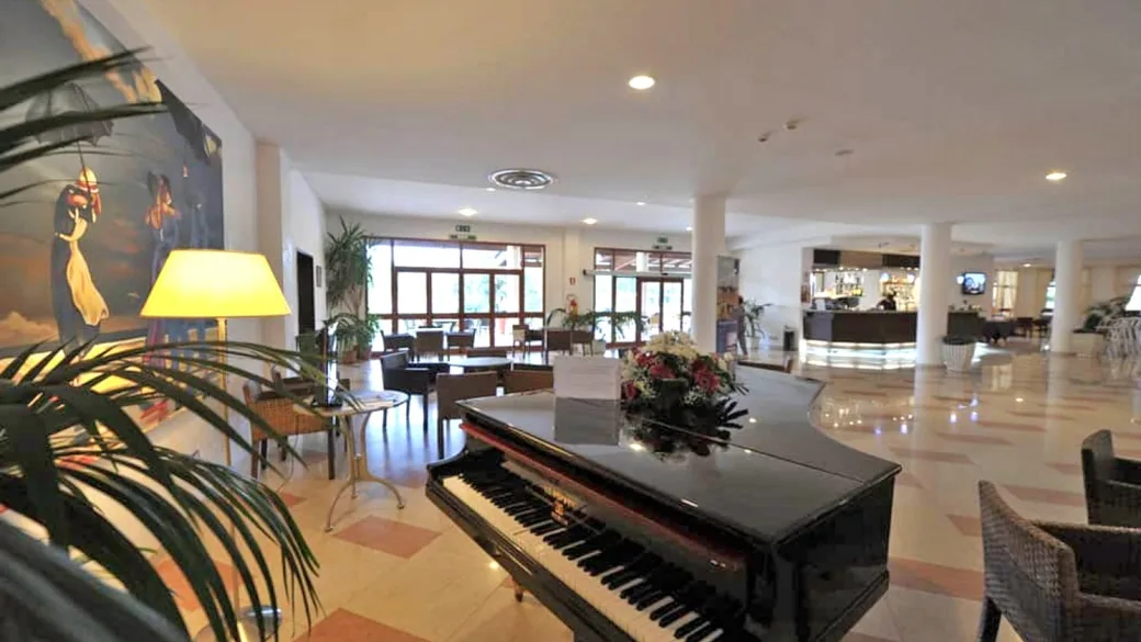Hall dell'hotel con pianoforte a coda, poltrone e reception