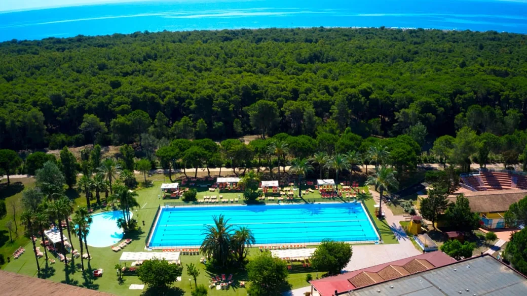 Veduta aerea della piscina olimpionica immersa nella pineta con vista mare