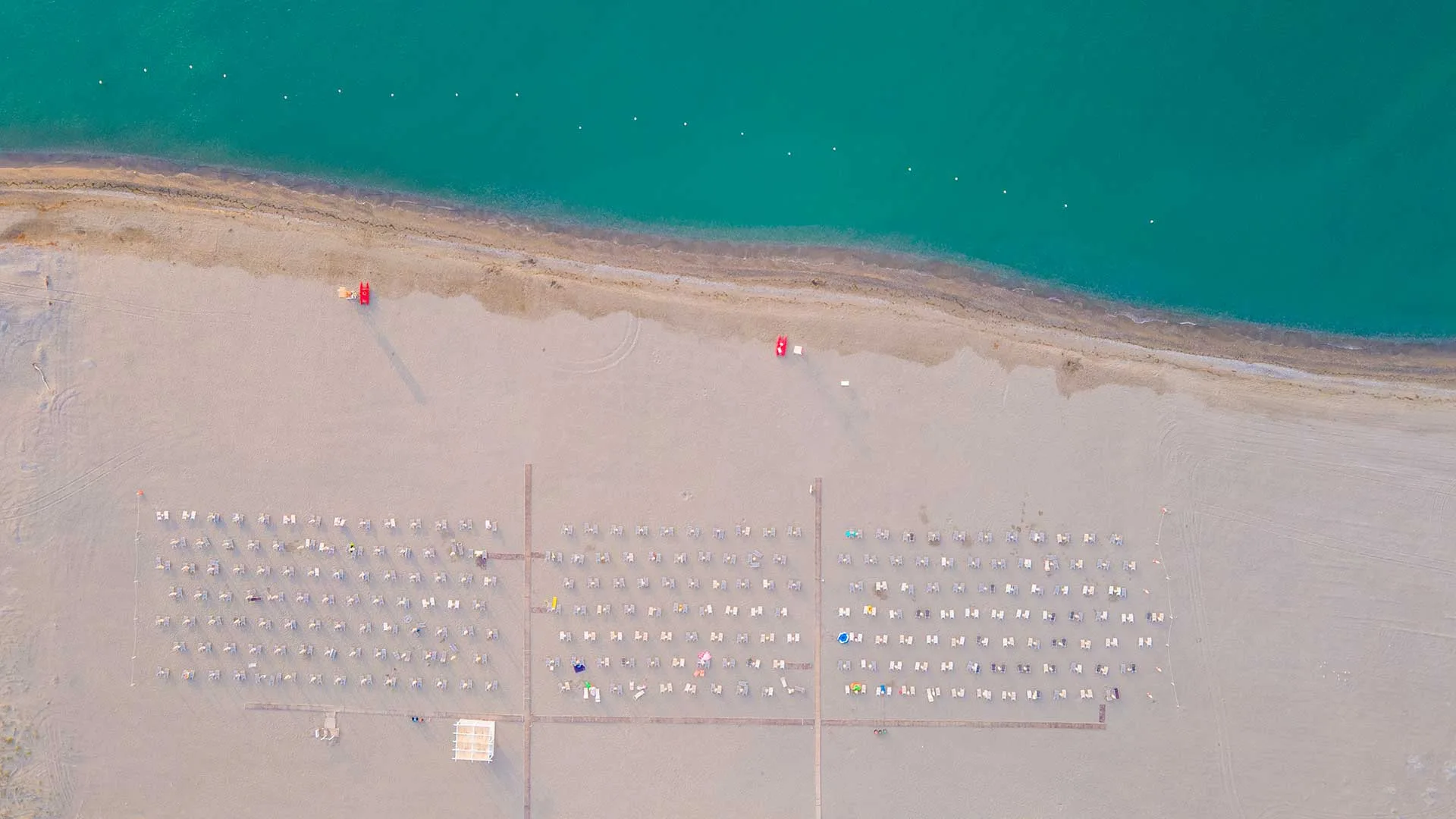 Vista aerea dall'alto della spiaggia con lettini ordinati e mare turchese
